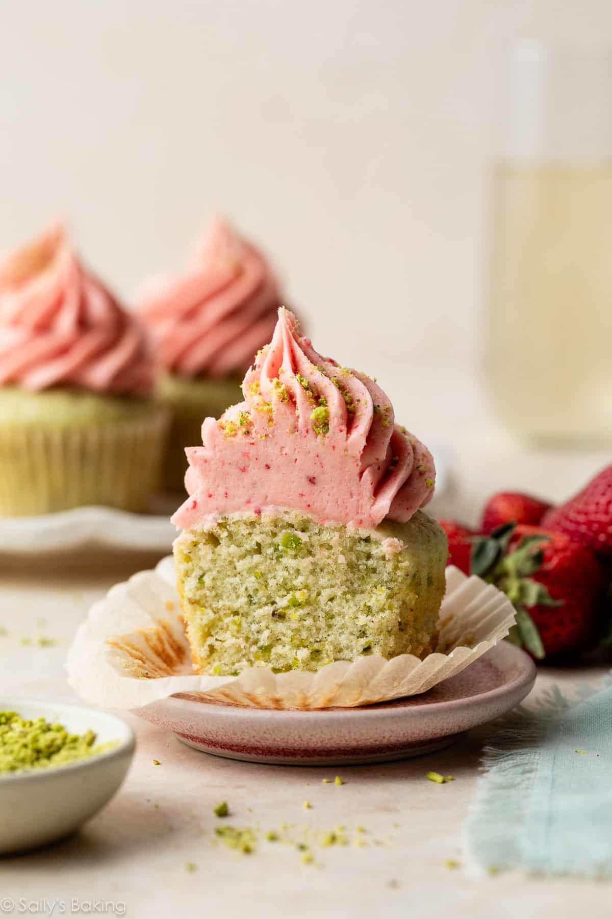 pistachio cupcake with strawberry buttercream unwrapped on a small plate.