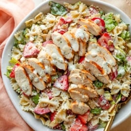 strawberry feta pasta salad in bowl with chicken on top.