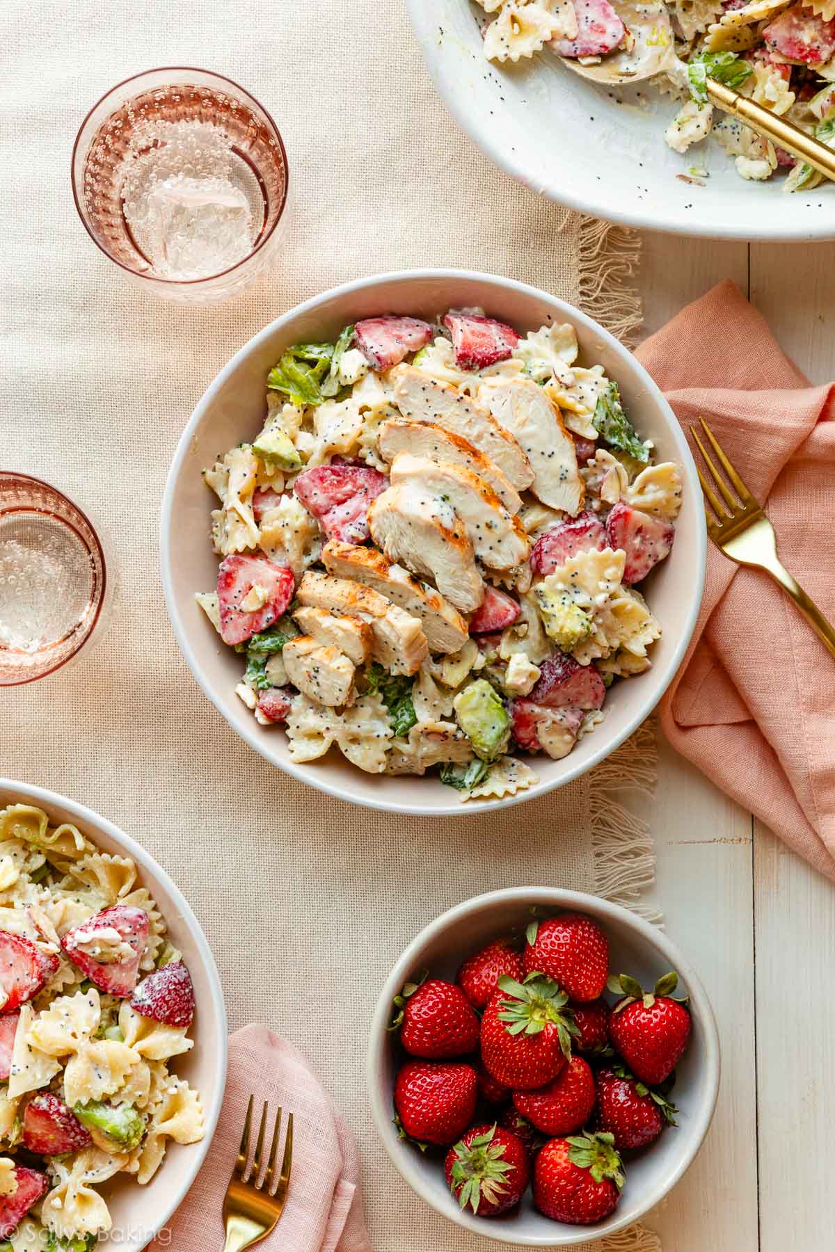 strawberry feta pasta salad in bowls with chicken on top.