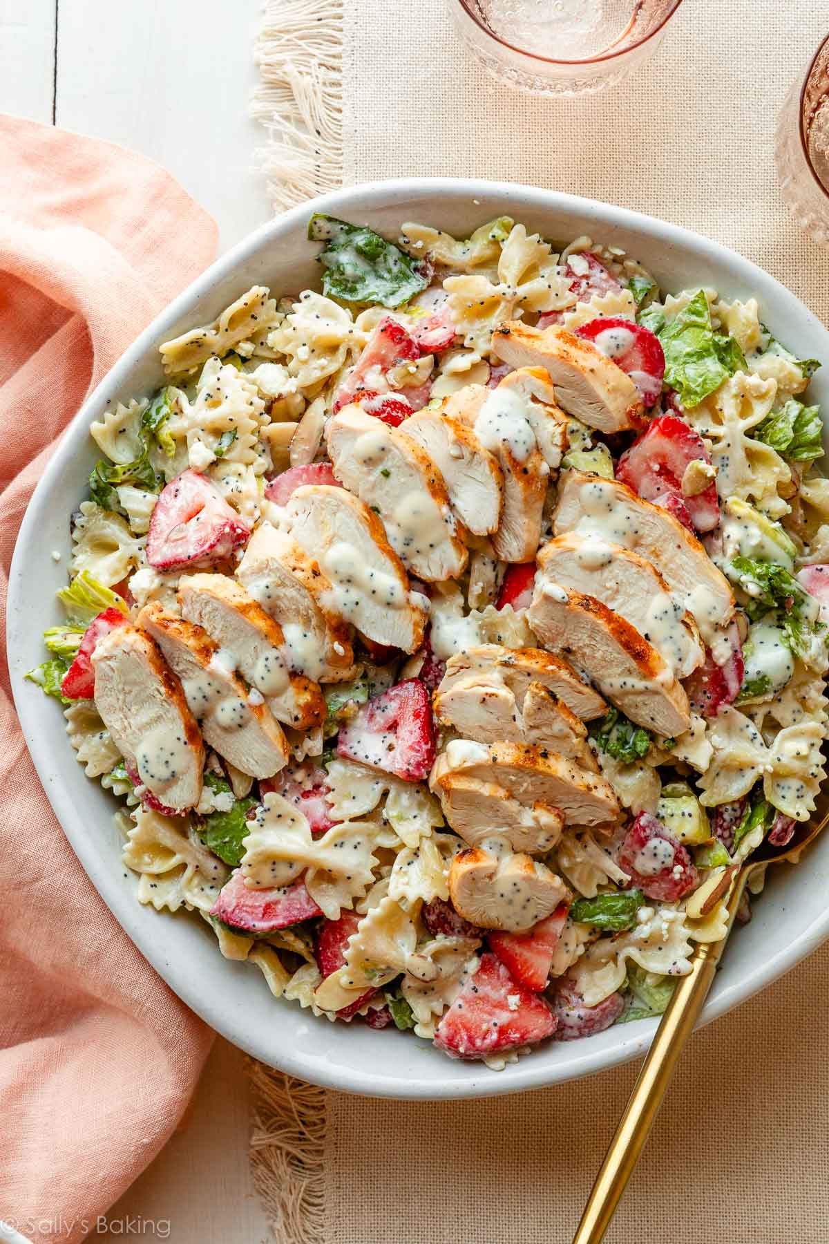 strawberry feta pasta salad in bowl with chicken on top.