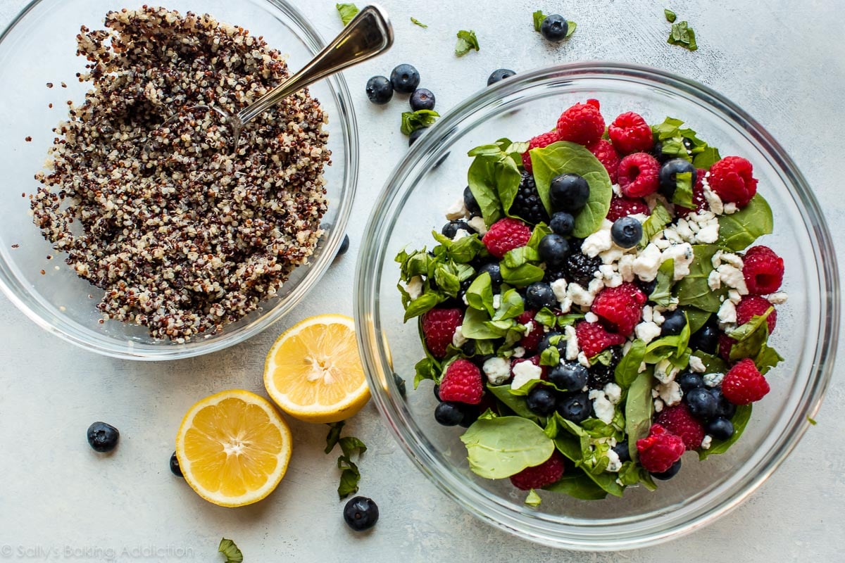 overhead image of quinoa in a glass bowl and spinach, berries, and cheese in a glass bowl