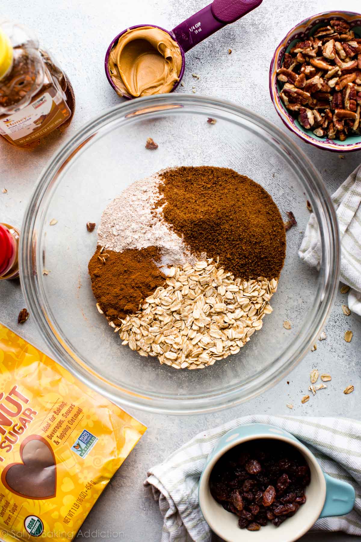 overhead image of ingredients for oatmeal raisin granola bars in glass bowls and measuring cups