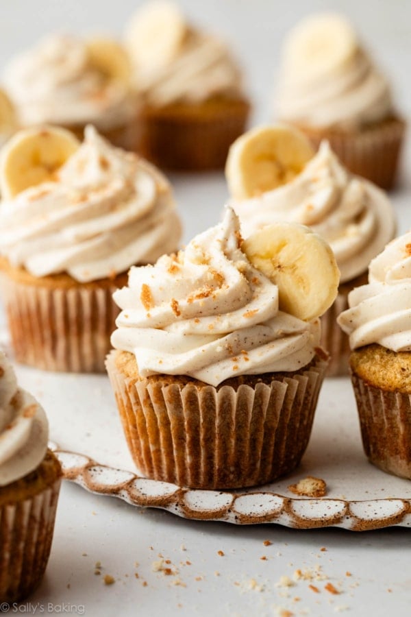 banana cupcakes with cinnamon cream cheese frosting, banana slice, and crushed nilla wafers on top.
