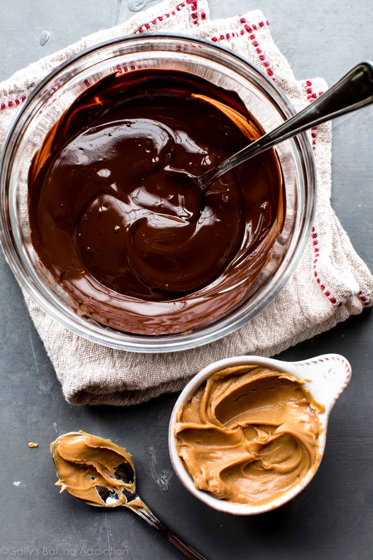melted chocolate in a glass bowl and peanut butter in a white measuring cup