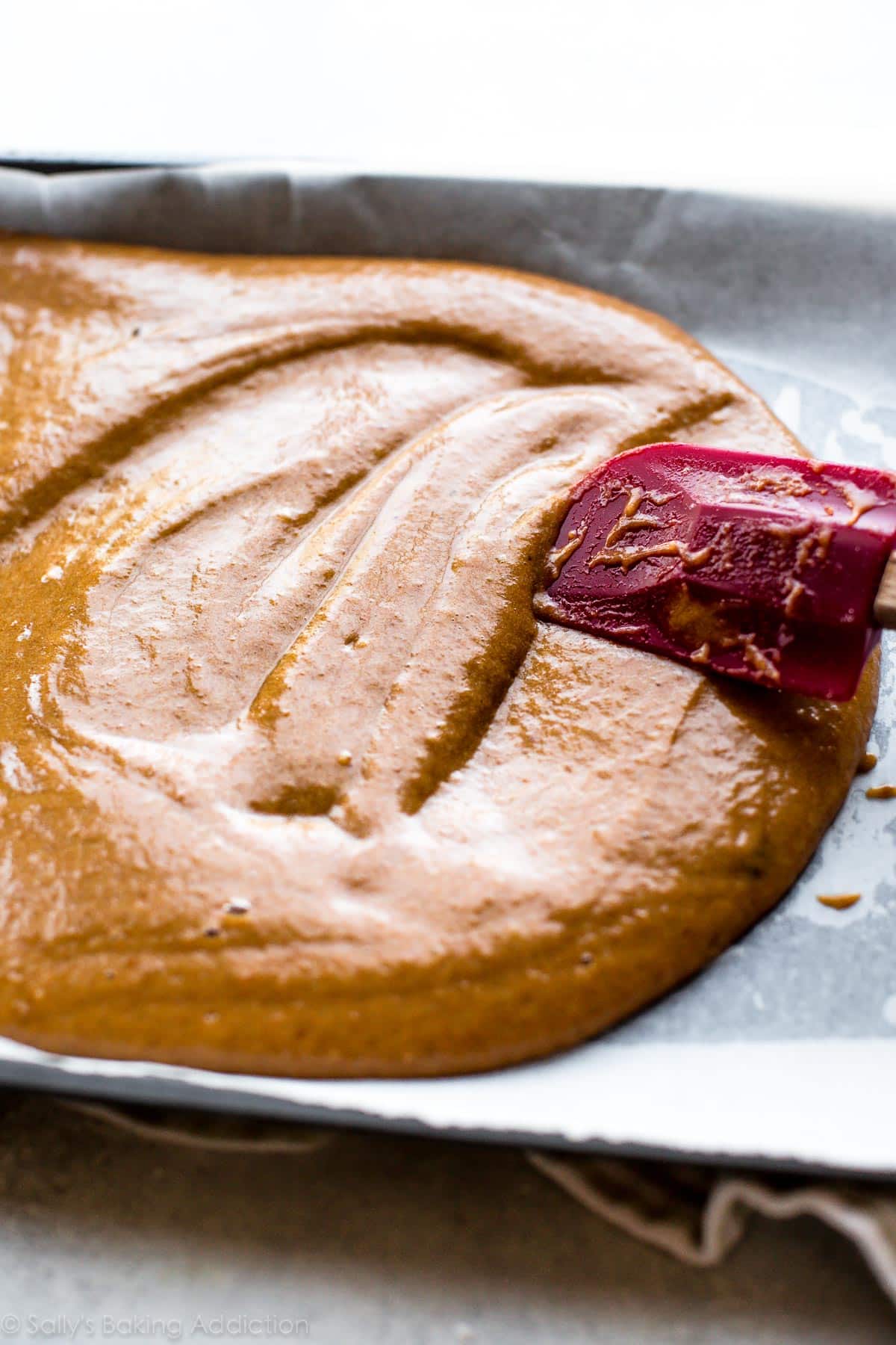 spreading pumpkin cake batter into pan