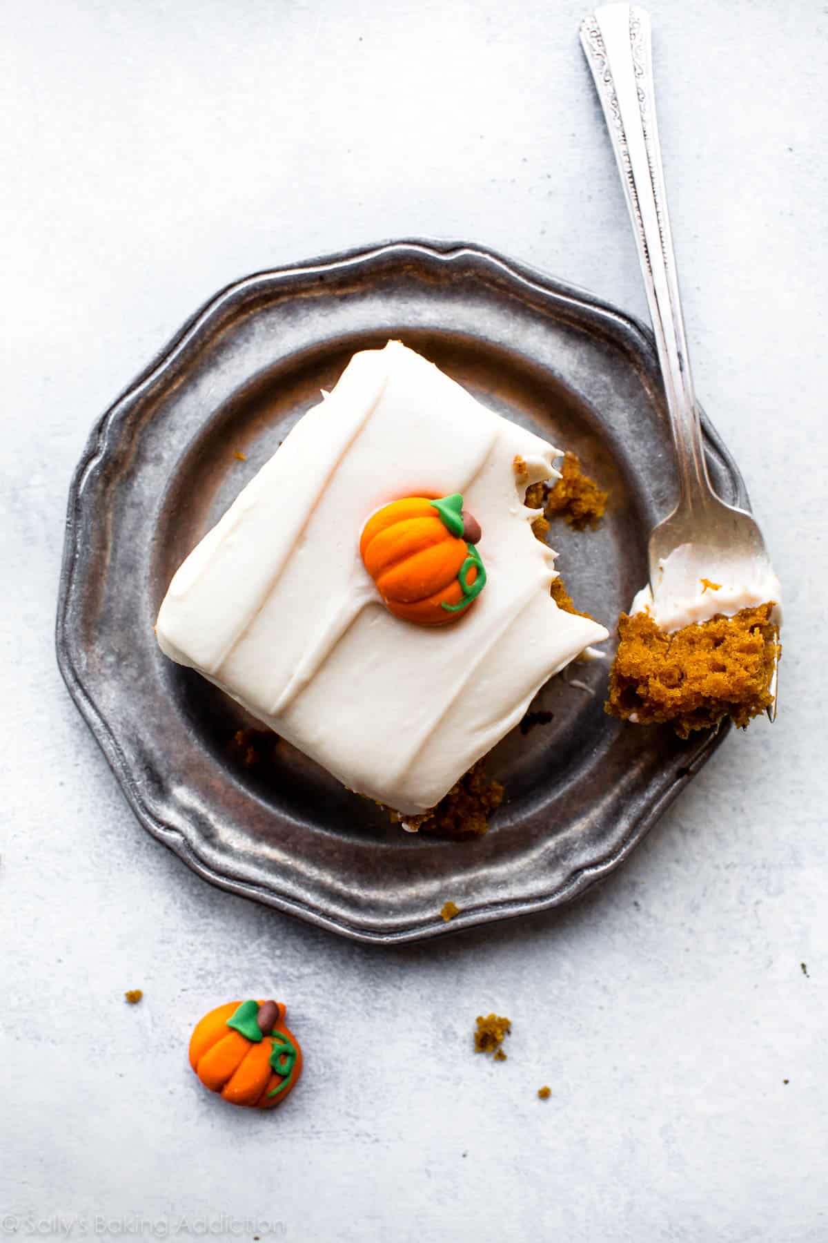 overhead image of a slice of pumpkin cake with cream cheese frosting on a silver plate