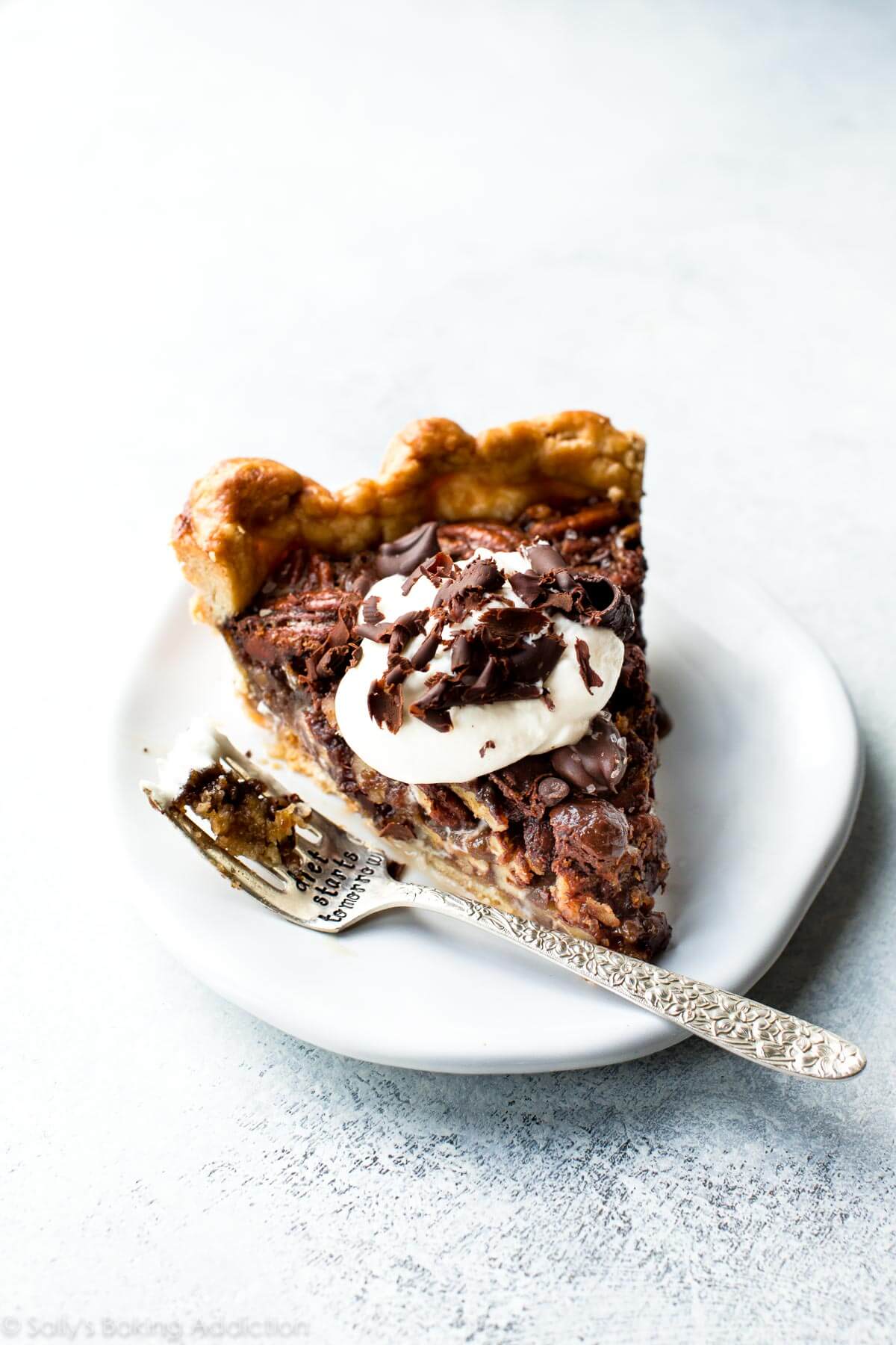 slice of dark chocolate pecan pie on a white plate