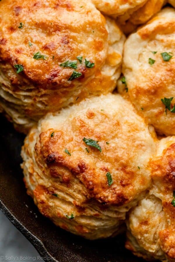close-up of cheddar cheese biscuits with parsley topping in cast iron skillet.