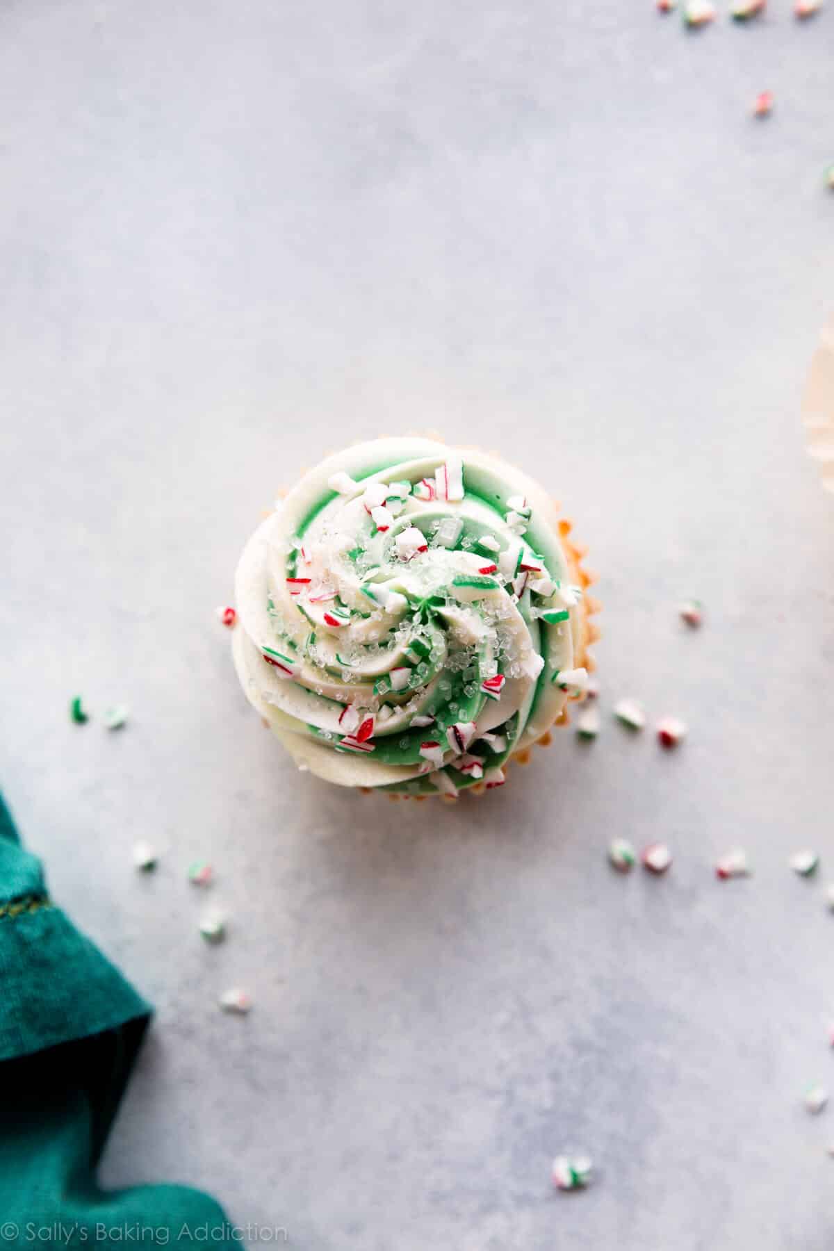 overhead image of a peppermint cupcake with white and green swirled white chocolate frosting with crushed candy canes and sprinkles
