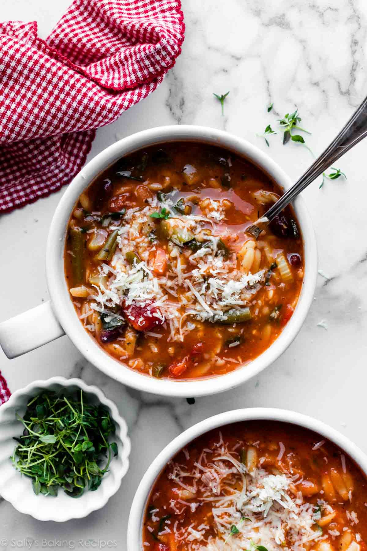 overhead photo of mugs of minestrone soup with grated parmesan on top.