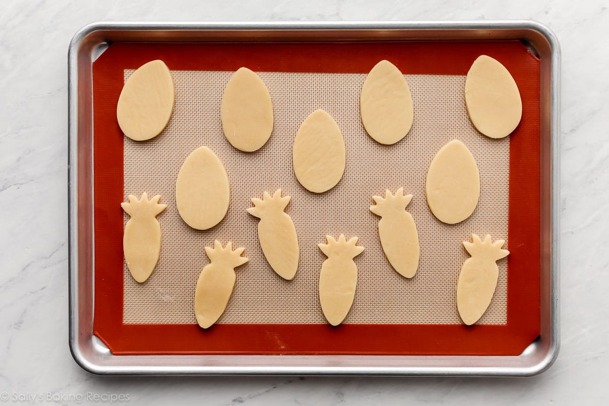 lined baking sheet with Easter egg and carrot-shaped cookies on top.