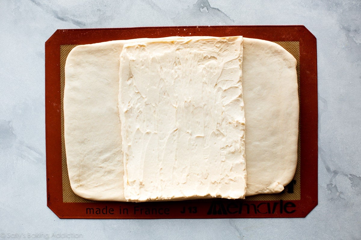 butter rectangle on top of croissant dough on a silpat baking mat