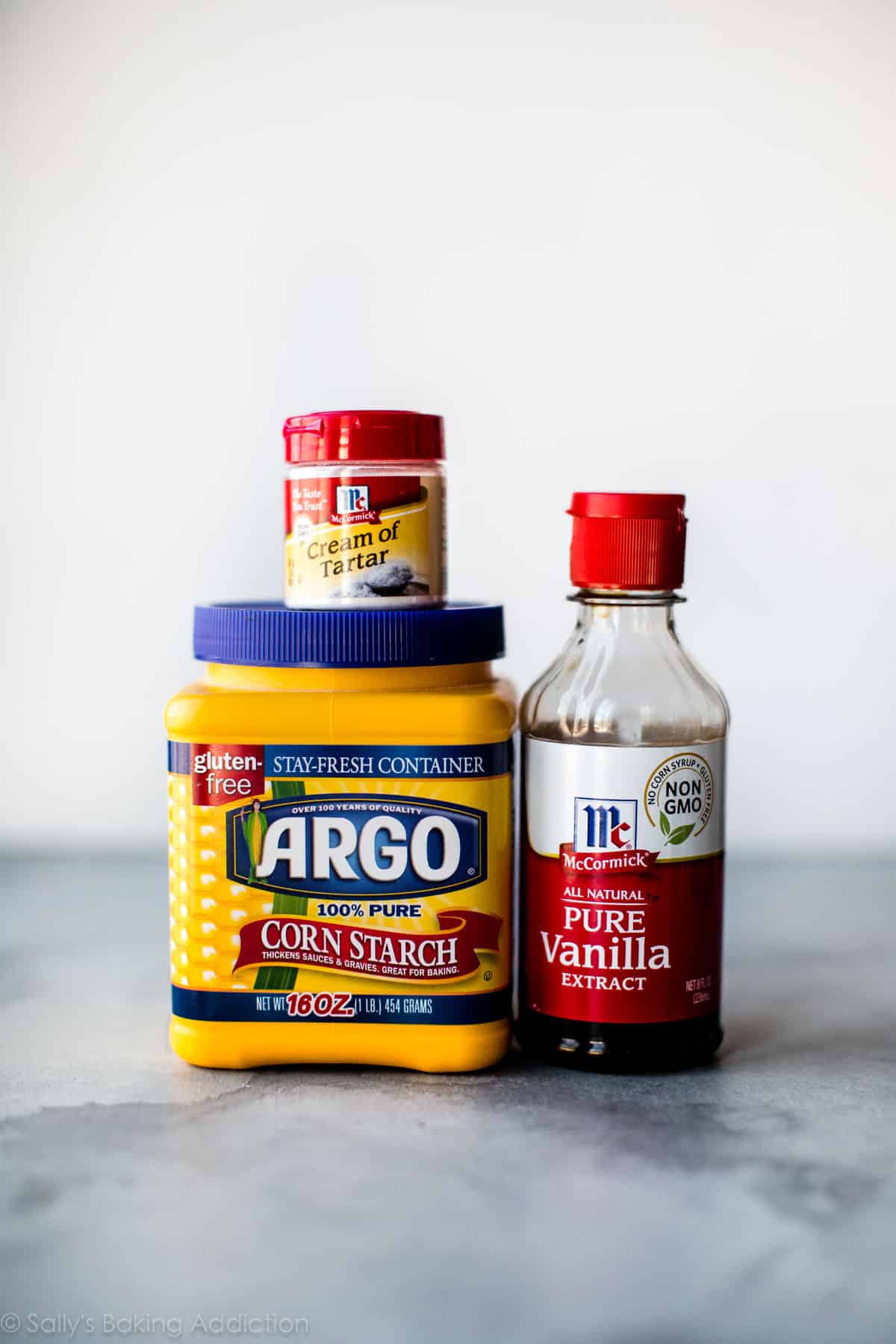 ingredients for pavlova including containers of cornstarch, cream of tartar, and vanilla extract