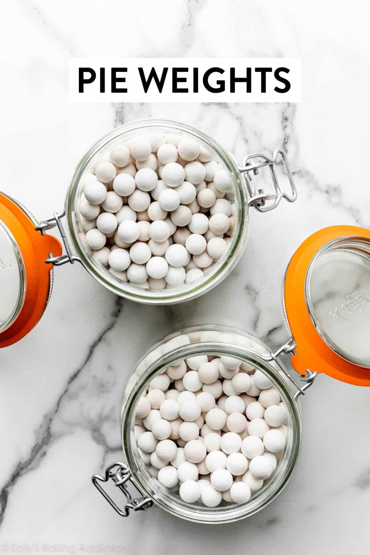 two jars of white pie weights on marble counter.