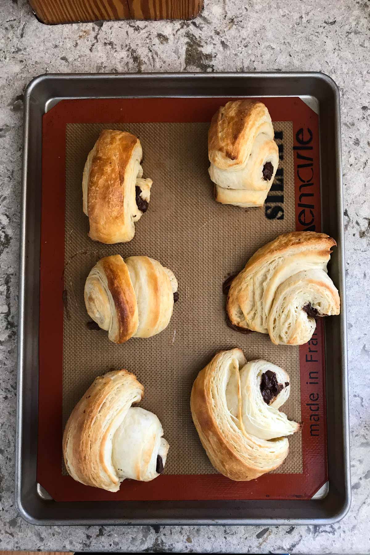 overhead image of chocolate croissants on a baking sheet after baking
