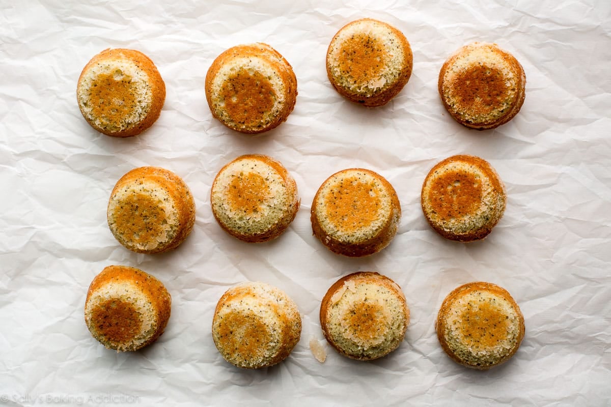 almond poppy seed tea cakes inverted from muffin pan onto parchment paper after baking