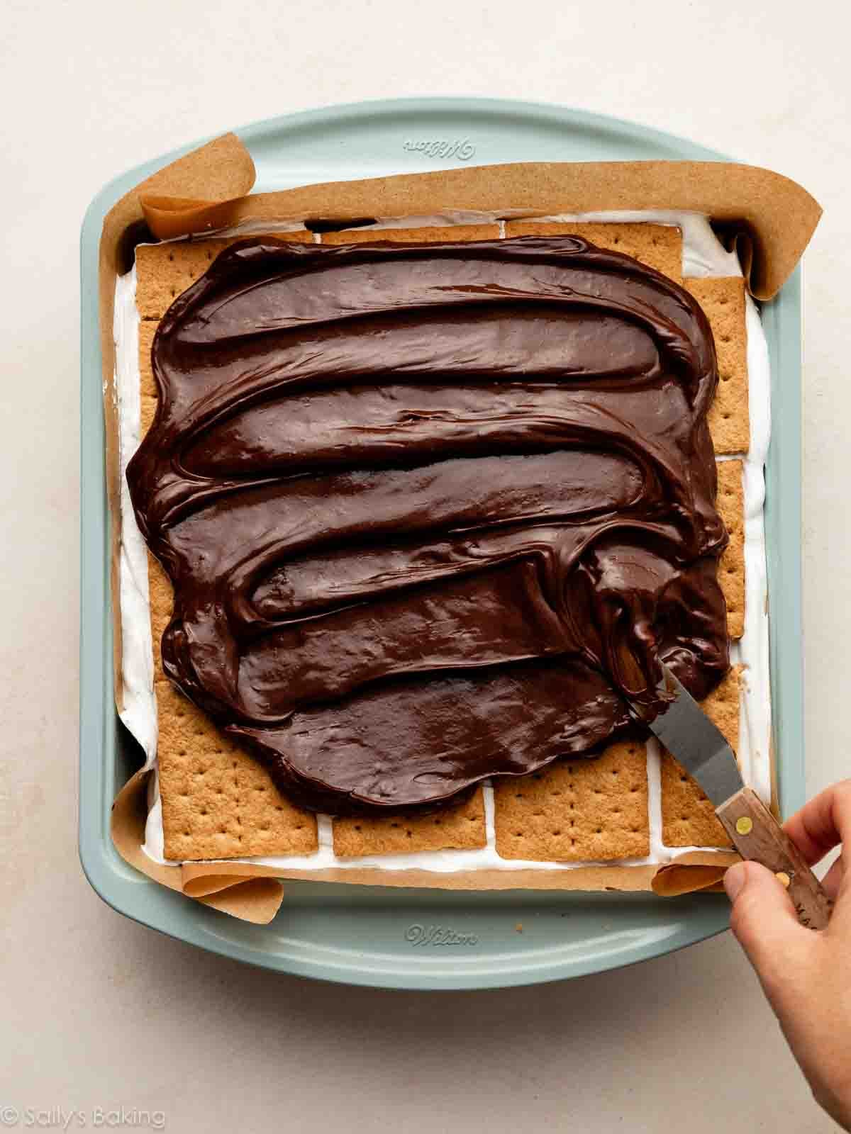 spreading chocolate ganache on graham crackers.