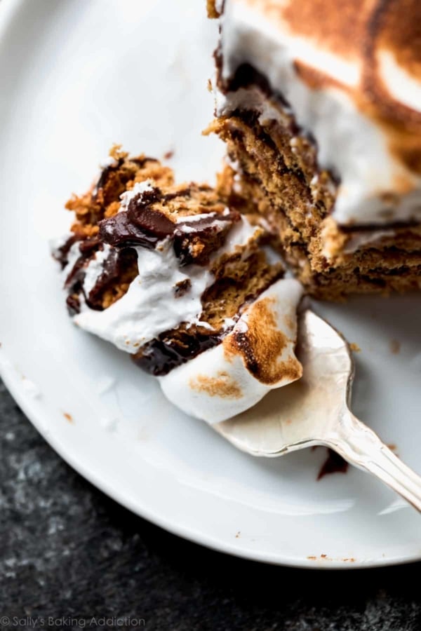 overhead image of slice of no-bake s'mores cake on a white plate with a fork