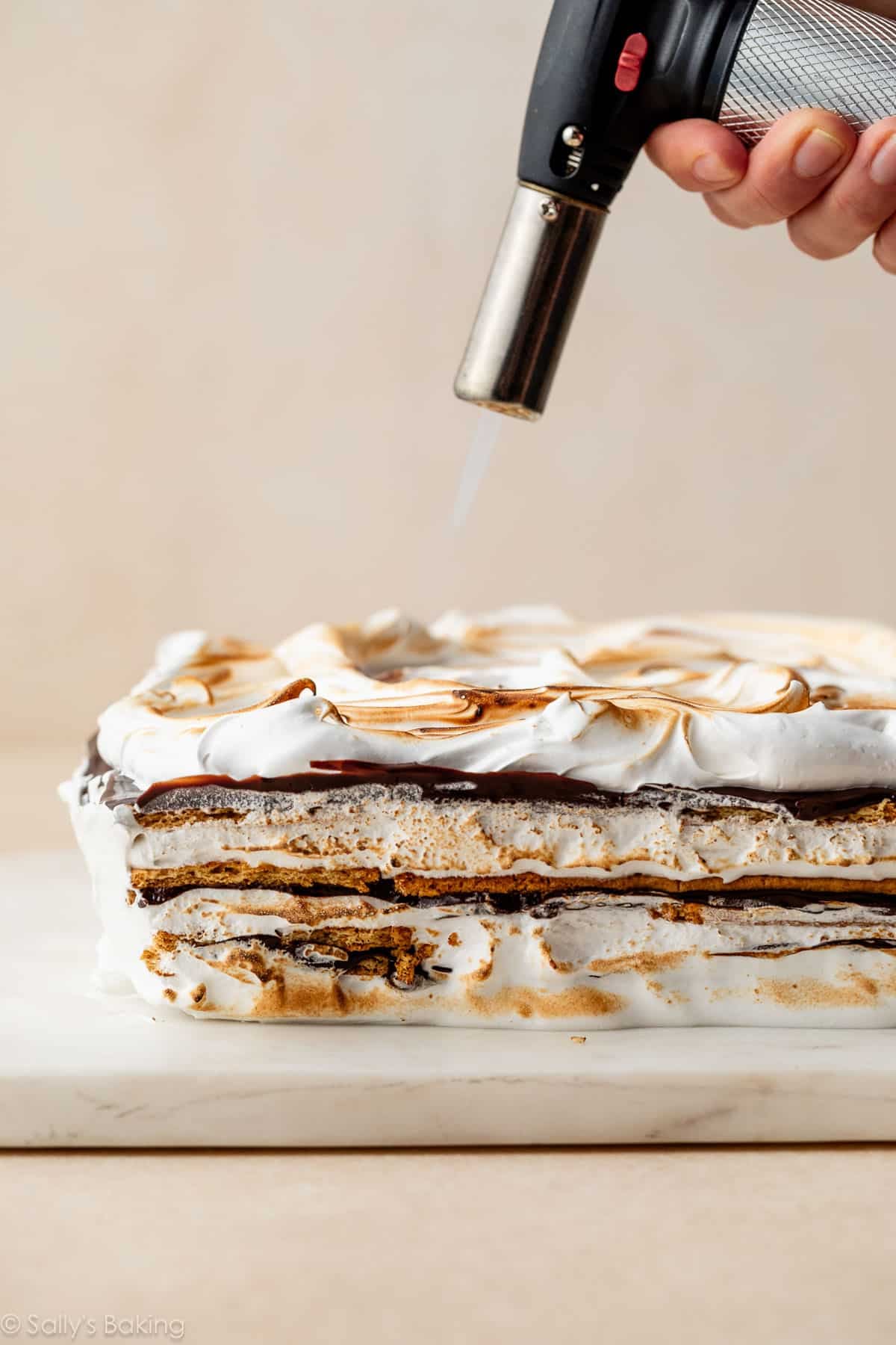 torching the marshmallow topping on smores cake with kitchen torch.