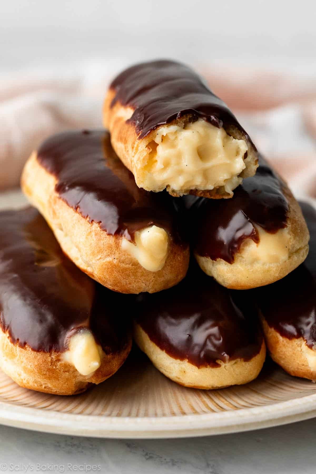 eclairs with chocolate on top and filled with pastry cream.