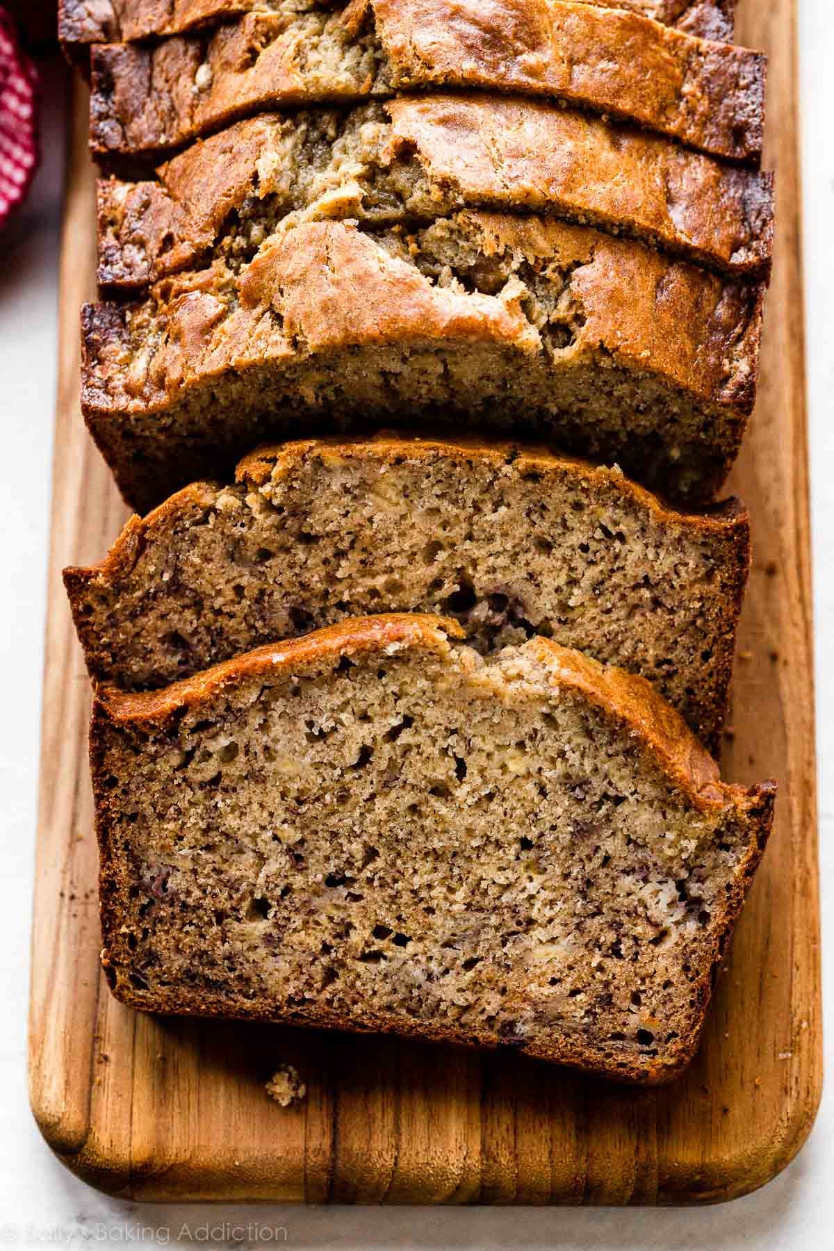 overhead photo of sliced banana bread on wooden cutting board.