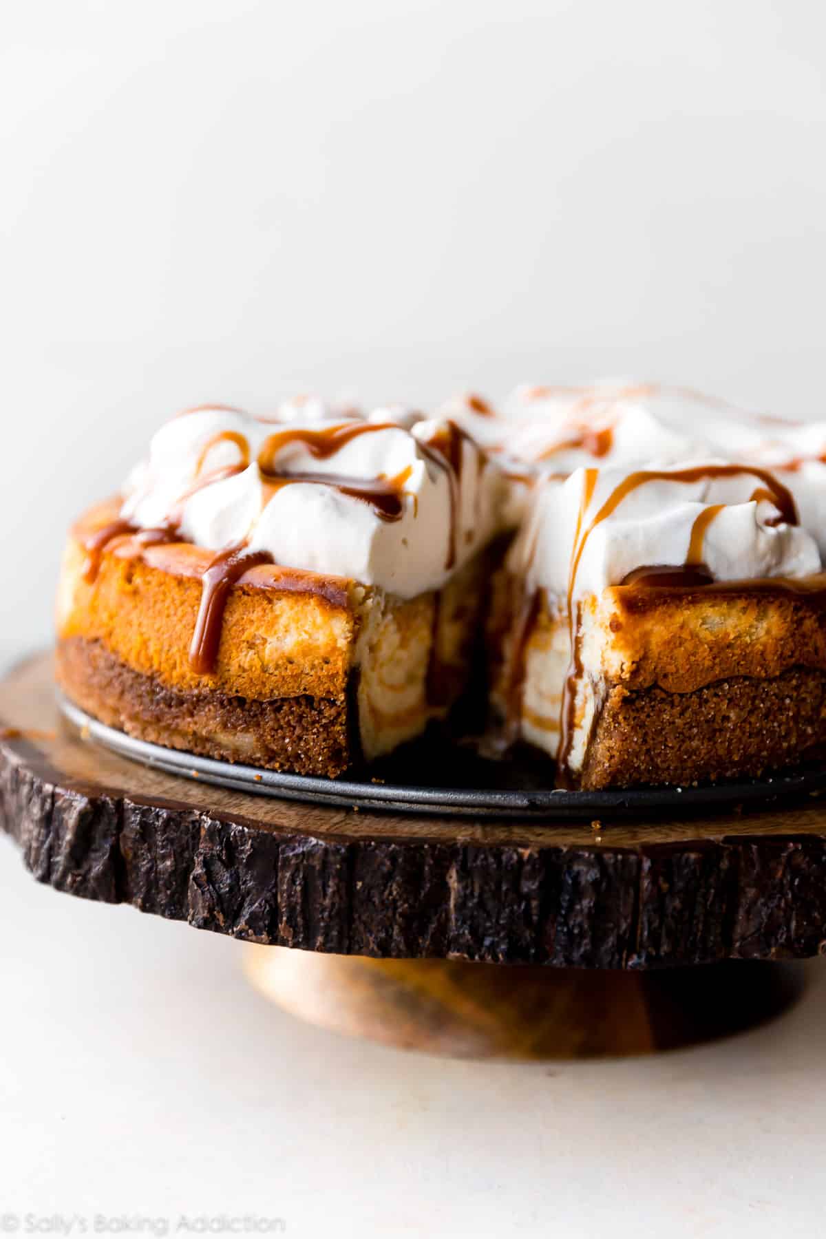 side view of pumpkin swirl cheesecake on a wood slice cake stand