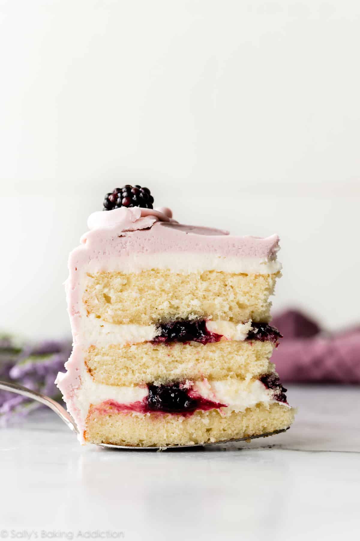 Slice of lavender butter cake with purple frosting and blackberry jam