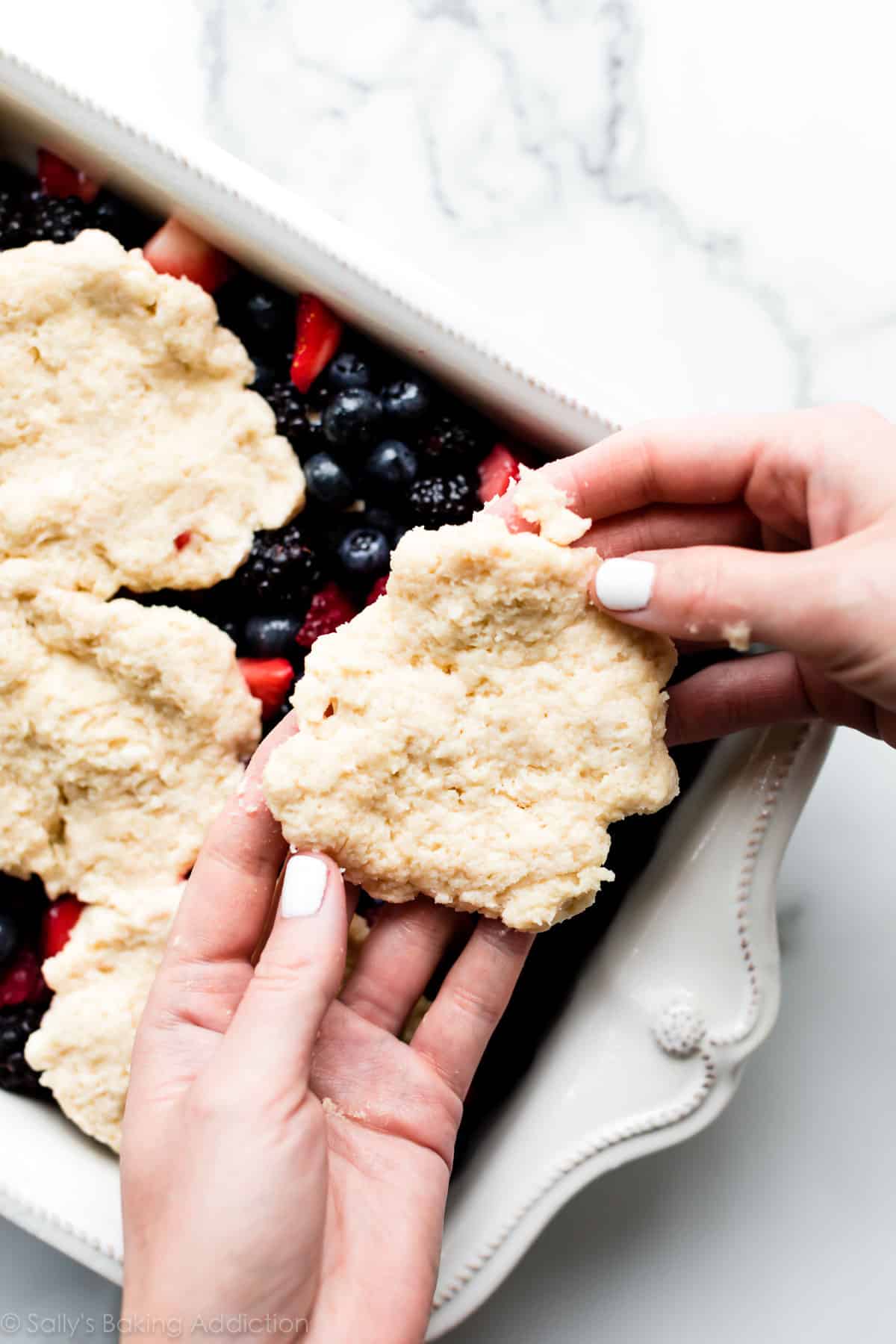hands shaping biscuit topping for cobbler