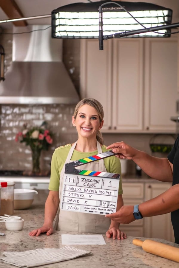Sally wearing green shirt and khaki branded apron with videography marker in place.