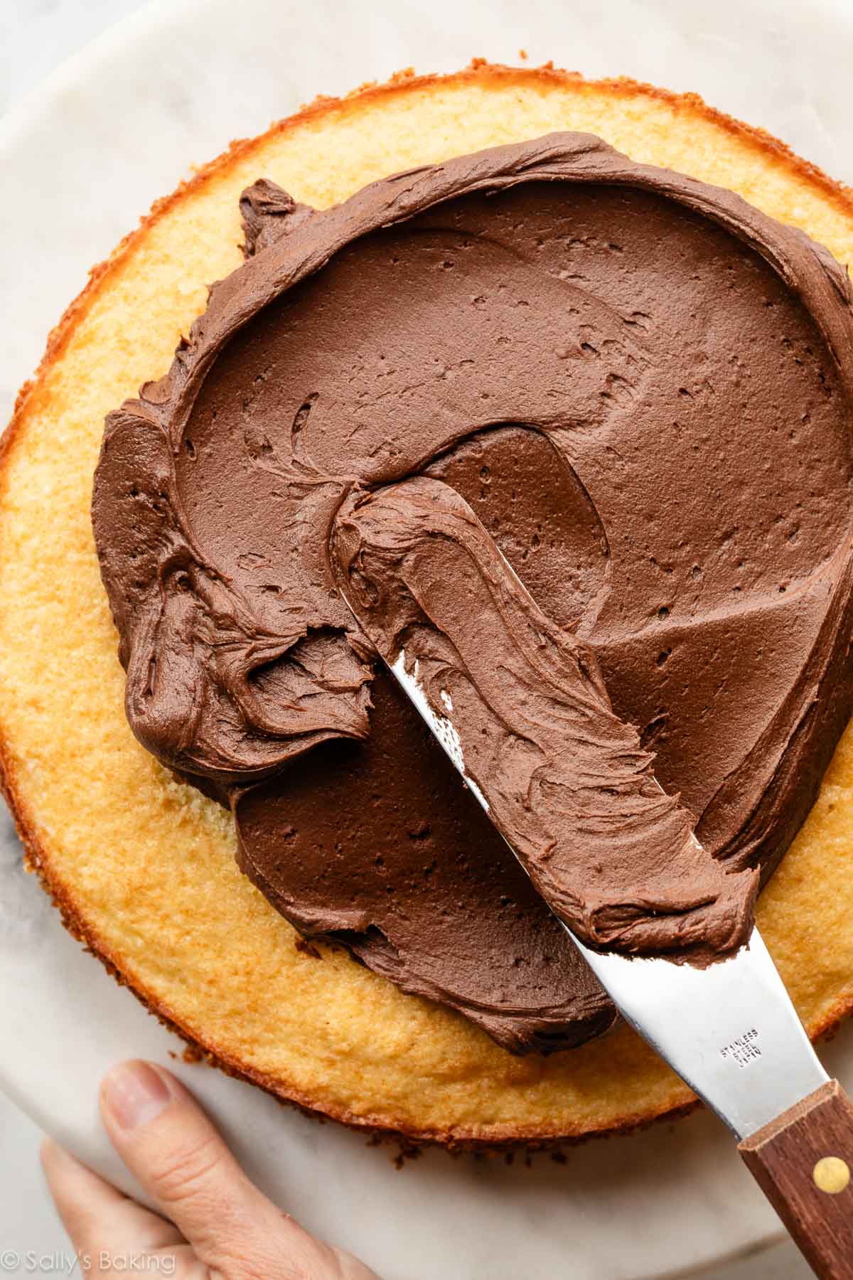 spreading chocolate frosting on cake layer.
