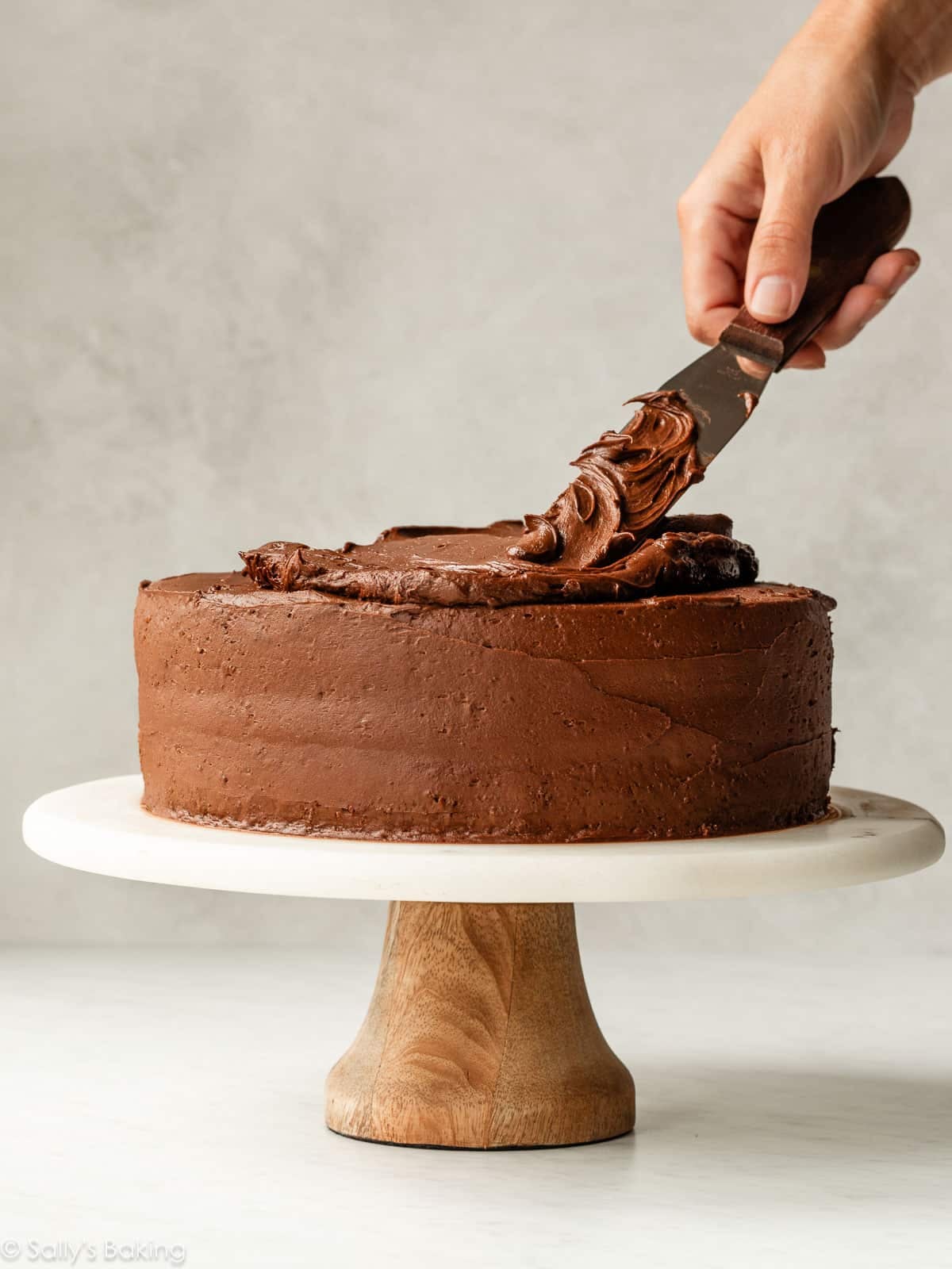 frosting cake on cake stand.