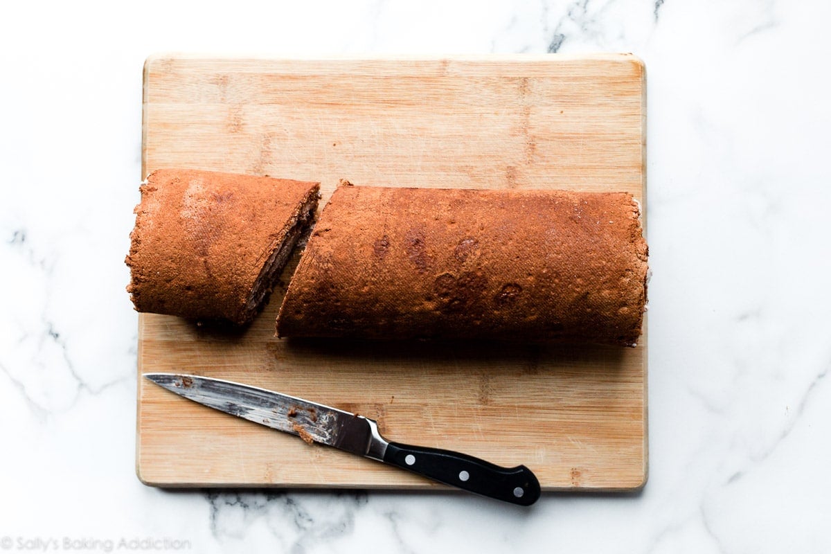 slicing yule log cake on a cutting board