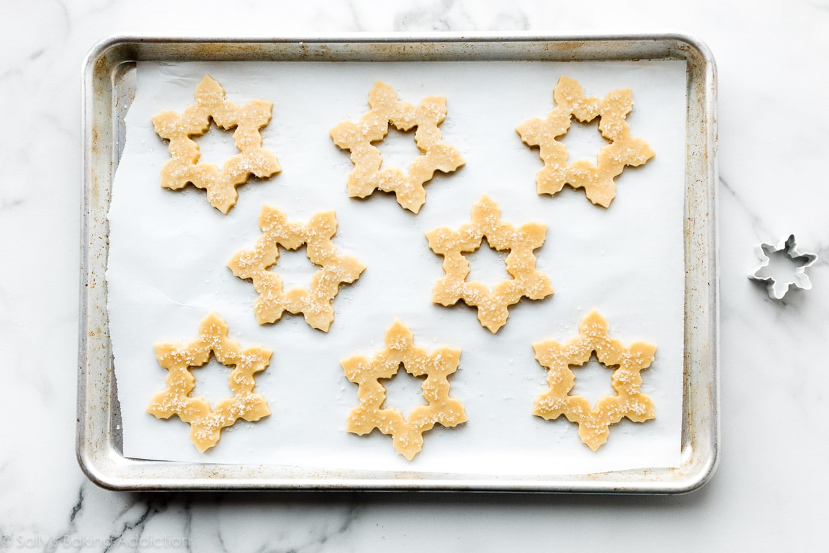 snowflake shaped sugar cookie dough on baking sheet