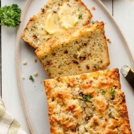 savory quick bread slices with butter, sun-dried tomatoes, parsley, and fresh basil.
