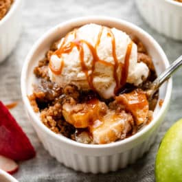 individual apple crumble in ramekin with ice cream and caramel on top
