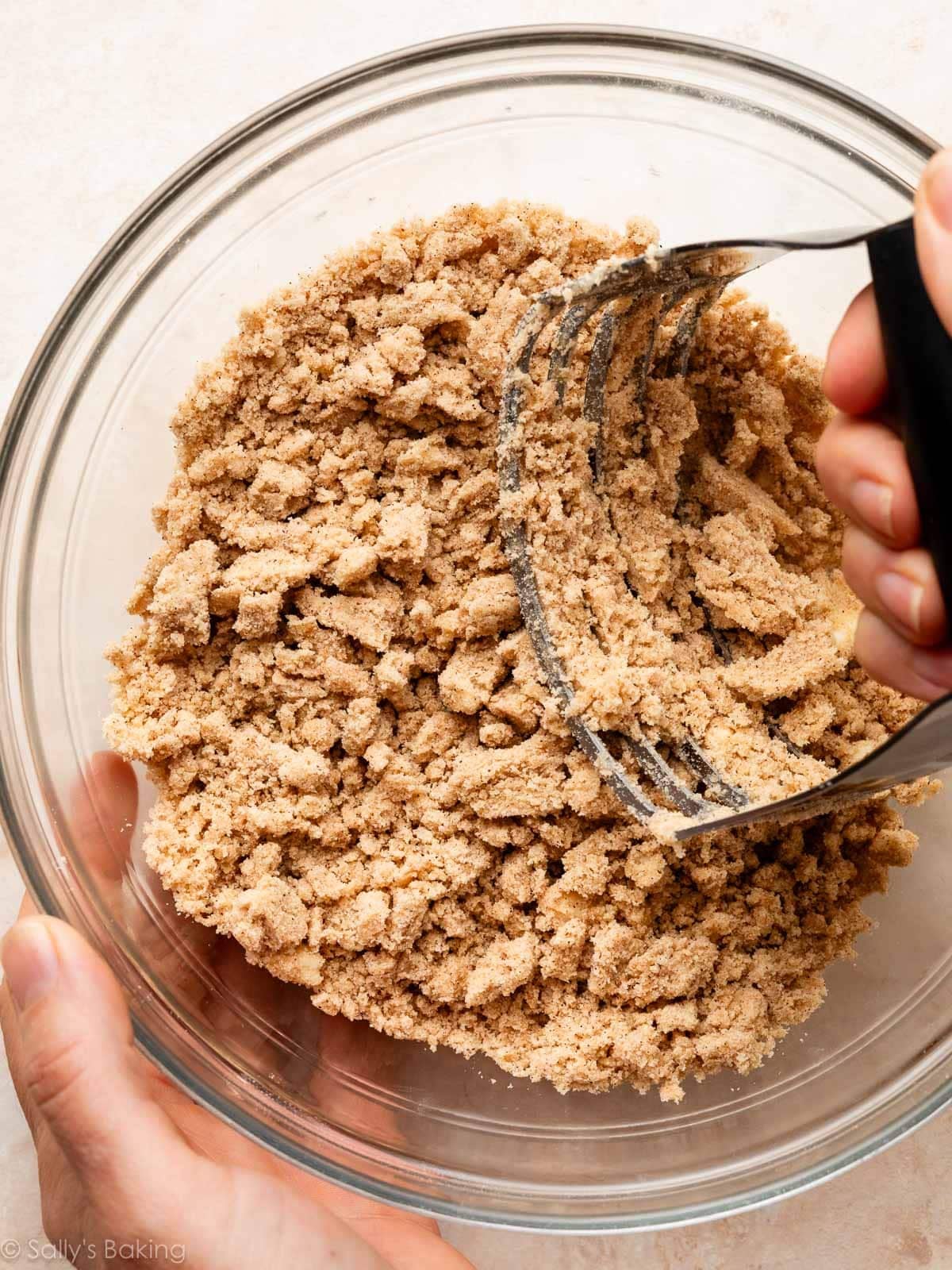 hands cutting crumble topping with pastry cutter.