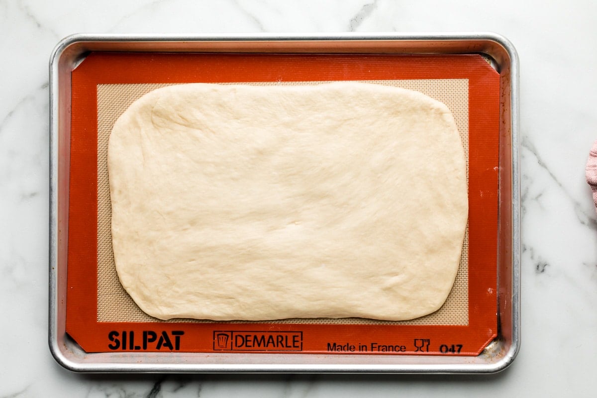 rolled out croissant bread dough on lined baking sheet