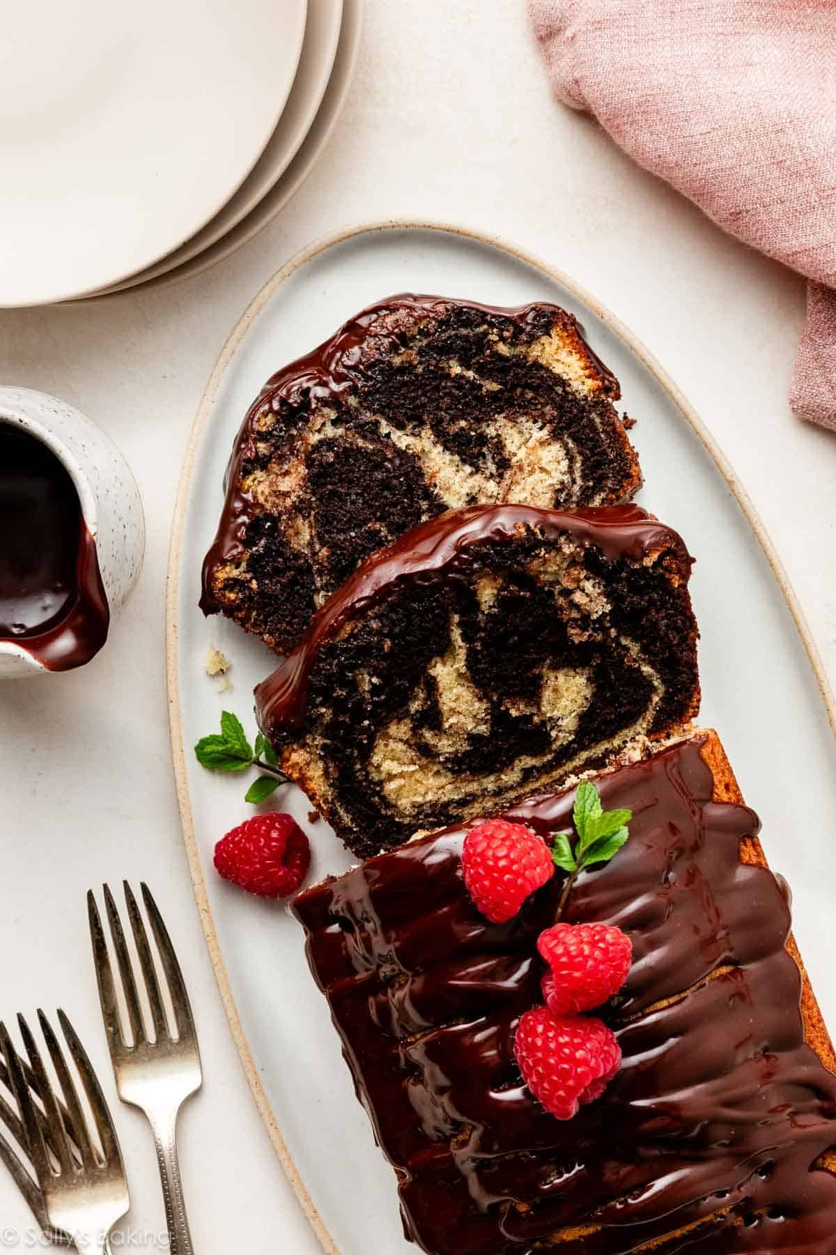 marble loaf cake with ganache and fresh raspberries on oval platter.