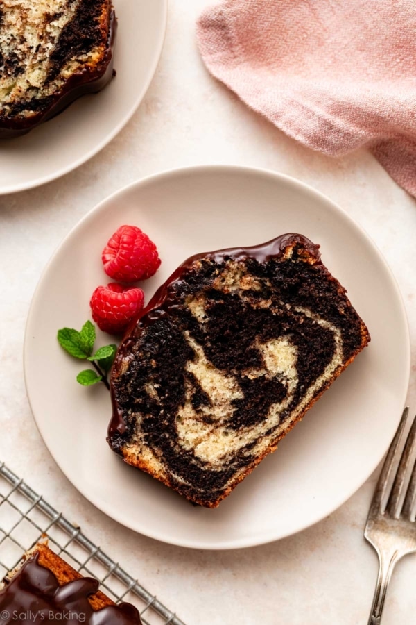 slice of marble loaf cake with fresh raspberries and mint on plate.