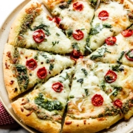 baked and sliced pesto pizza with mozzarella cheese and tomatoes.