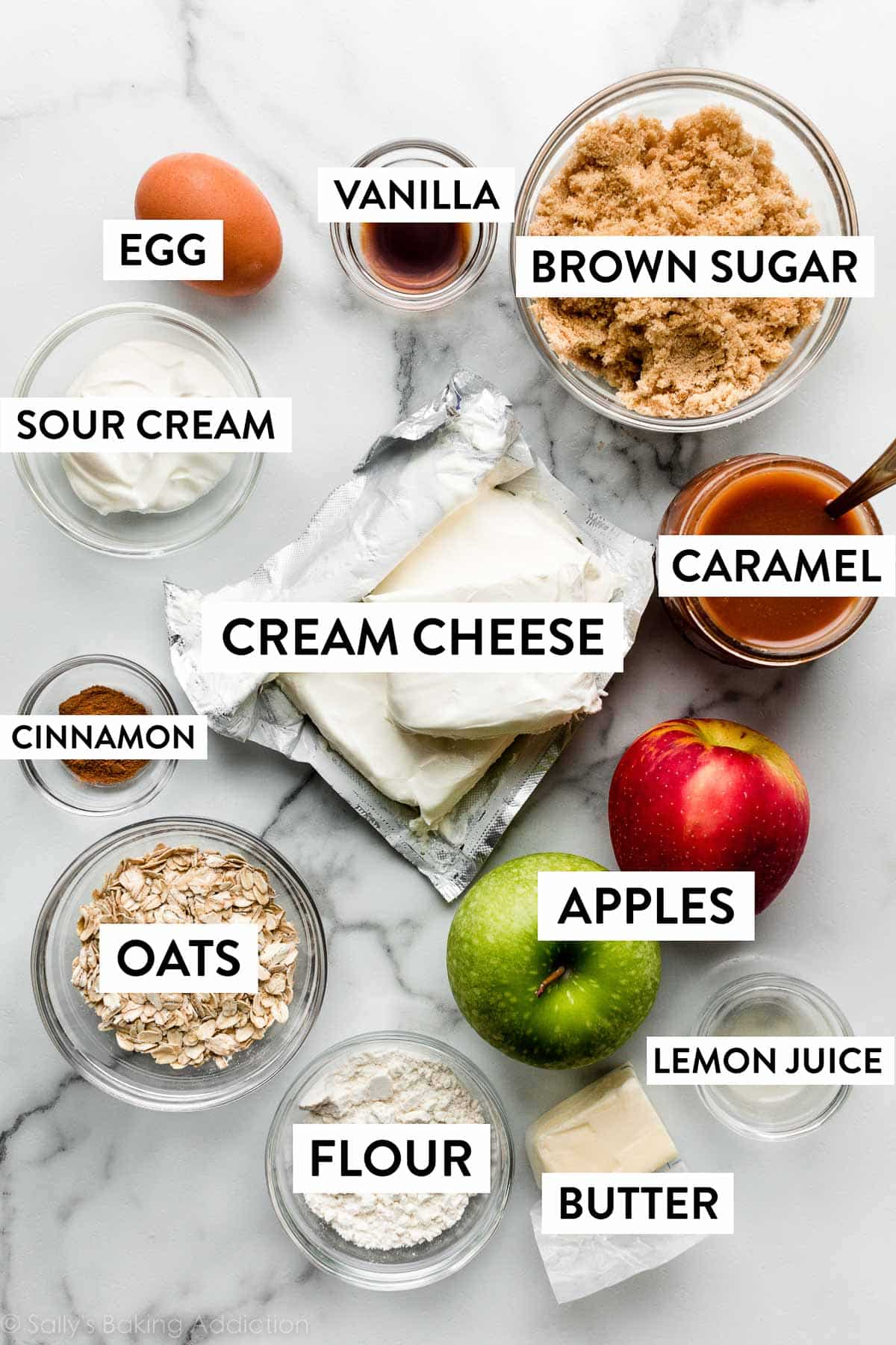 cream cheese, apples, lemon juice, brown sugar, oats, egg, and other ingredients laid out on marble counter.