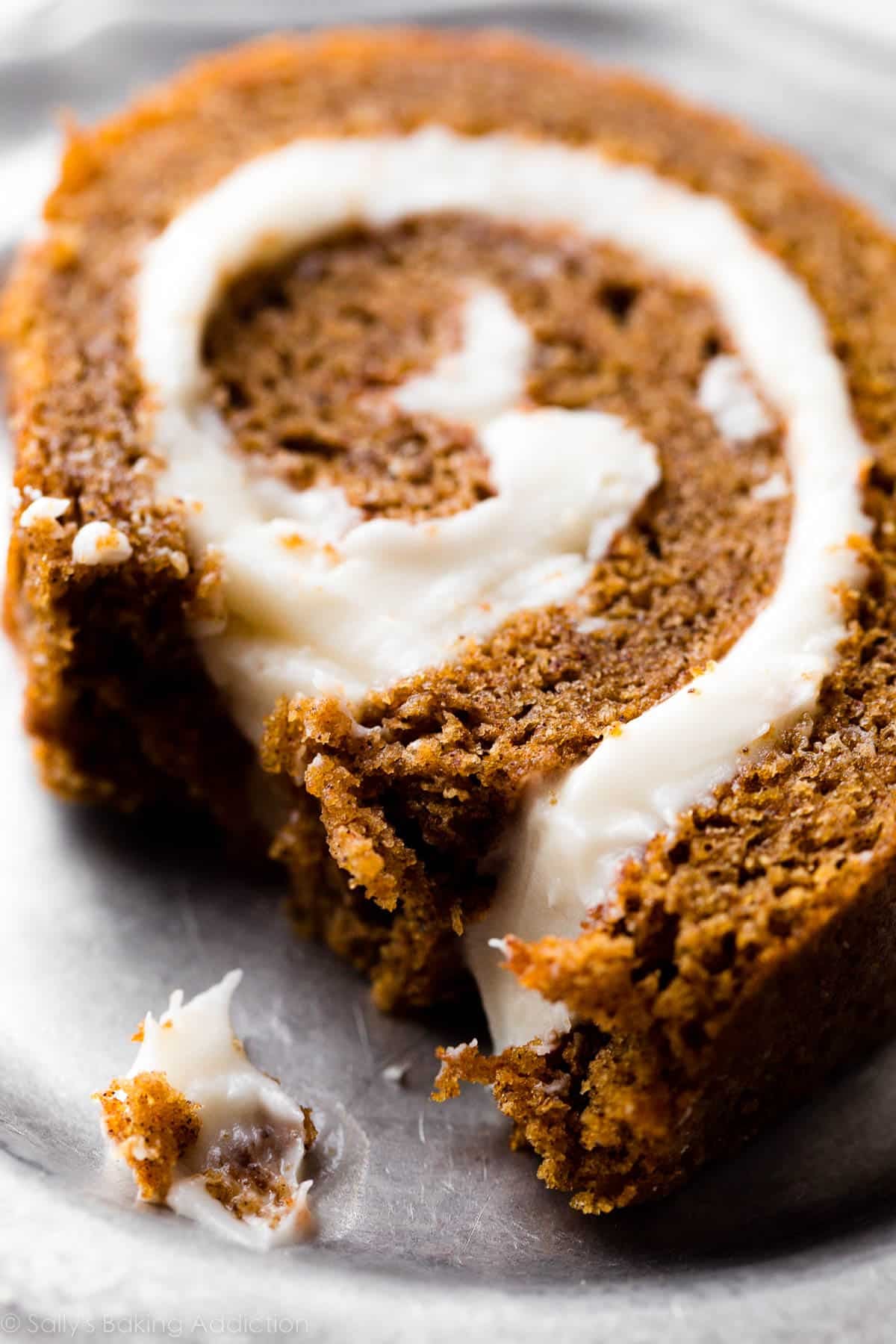 pumpkin roll slice on silver plate with piece taken out to show center.