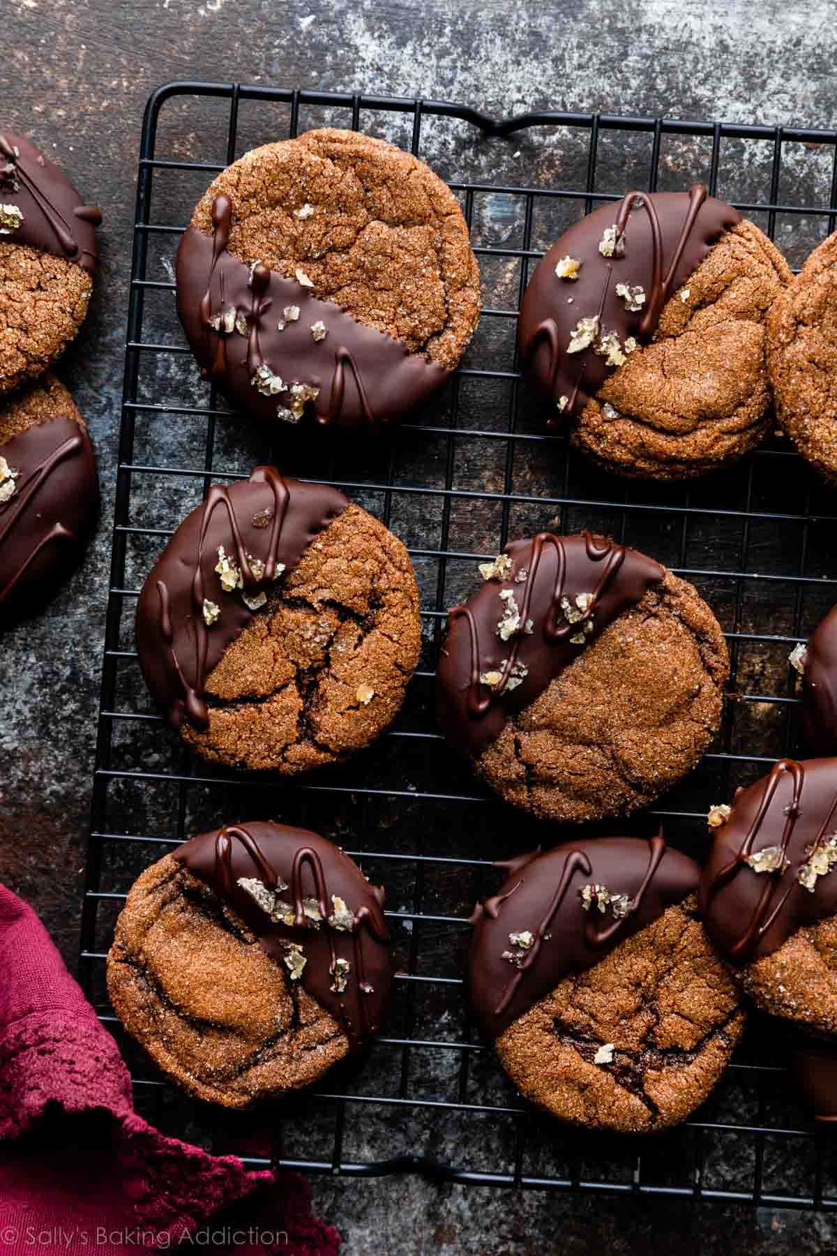 8-9 dark chocolate ginger cookies dipped in and drizzled with dark chocolate and set on black cooling rack.