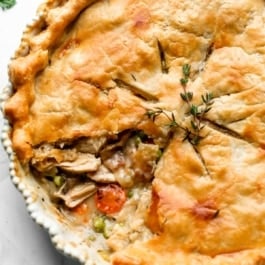 turkey pot pie with 1 slice removed to show carrots, peas, turkey, and gravy filling.