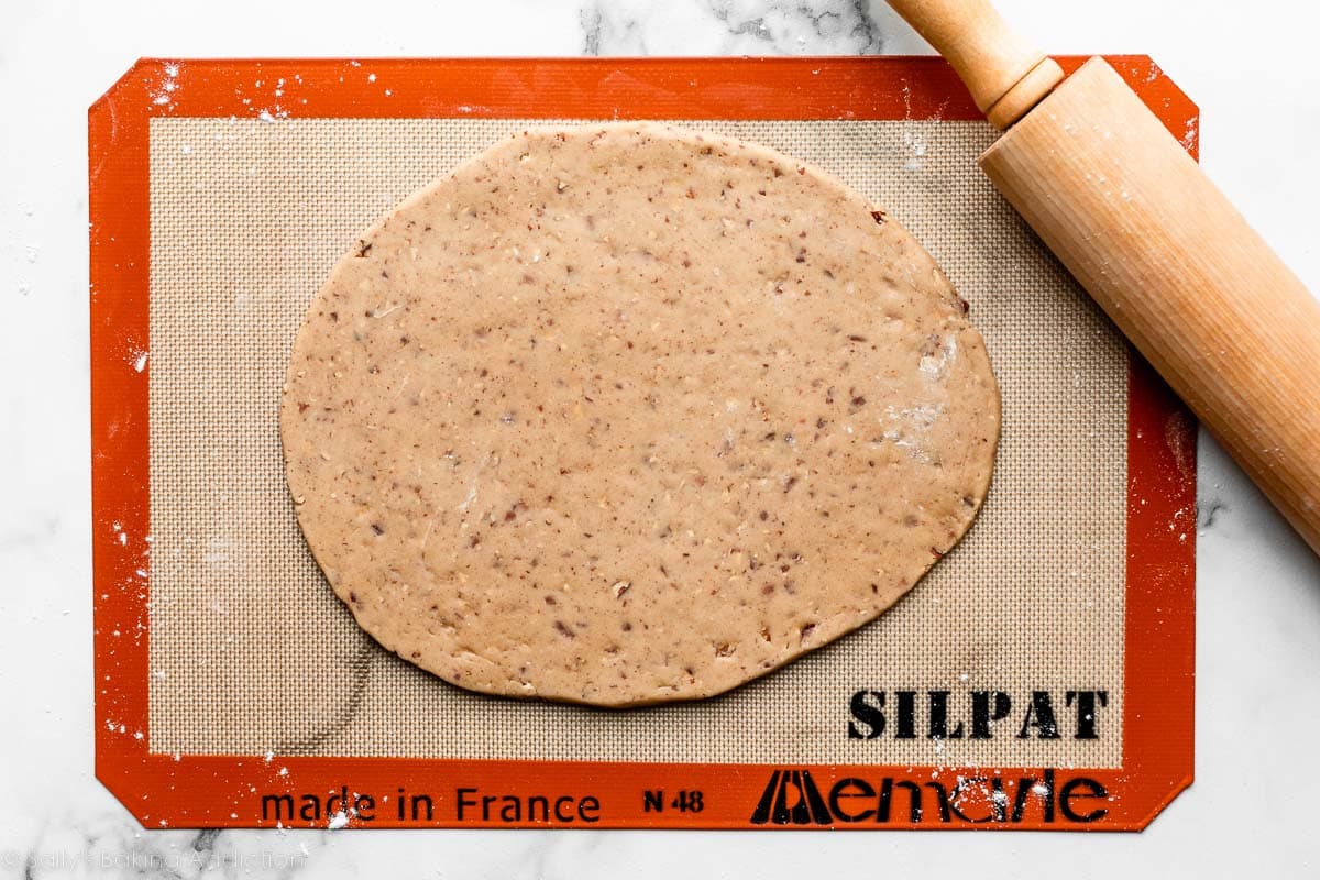 rolled out pecan-speckled dough on silicone baking mat.