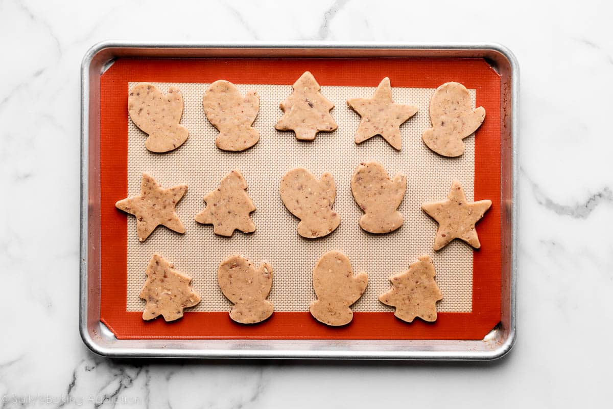 brown sugar pecan cookies cut into Christmas shapes and arranged on silicone baking mat-lined baking sheet.