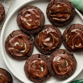 chocolate cookies with melted Andes chocolate mint spread on top on white plate.