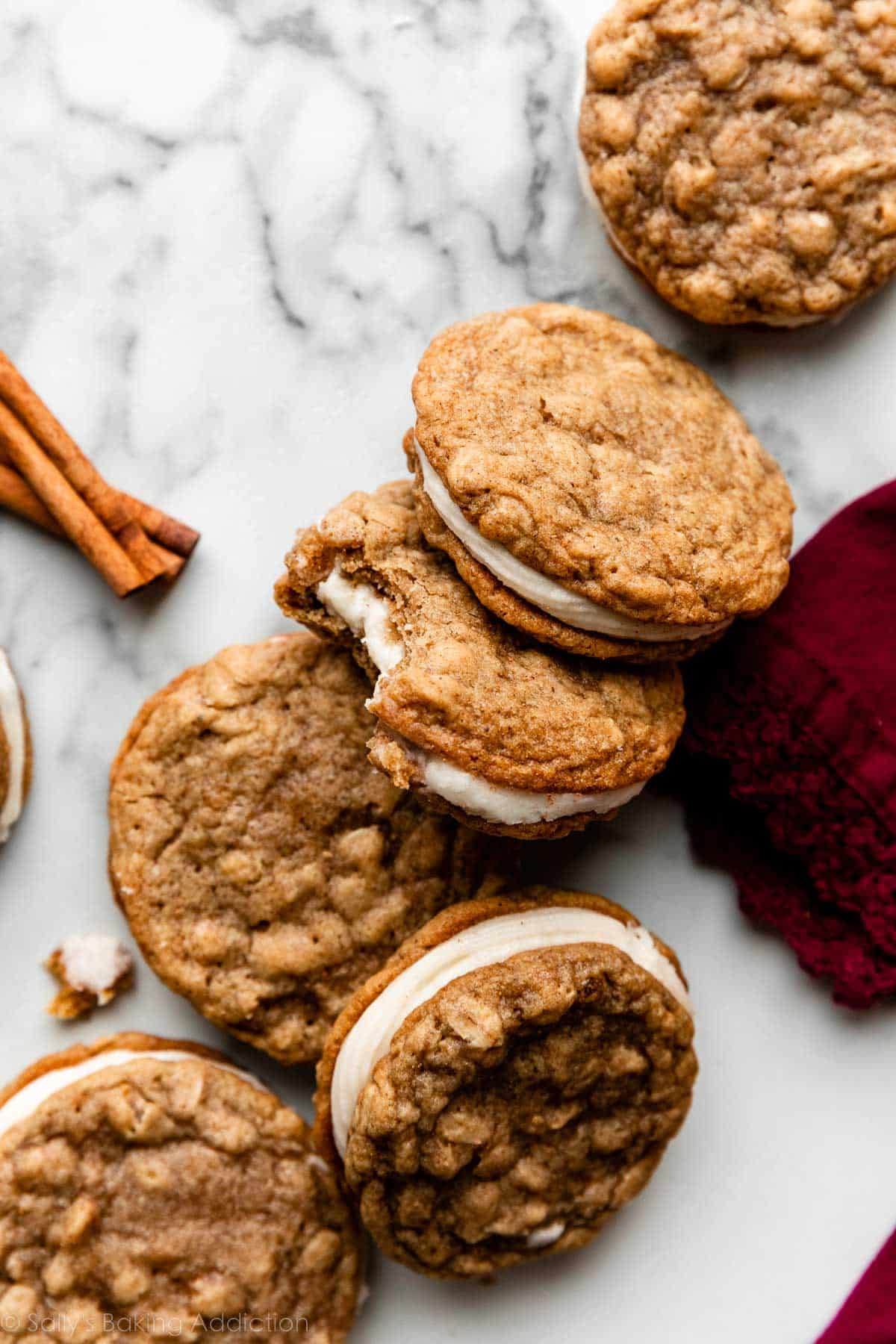 oatmeal cream pies with eggnog buttercream arranged on marble counter with a cinnamon stick for decor.