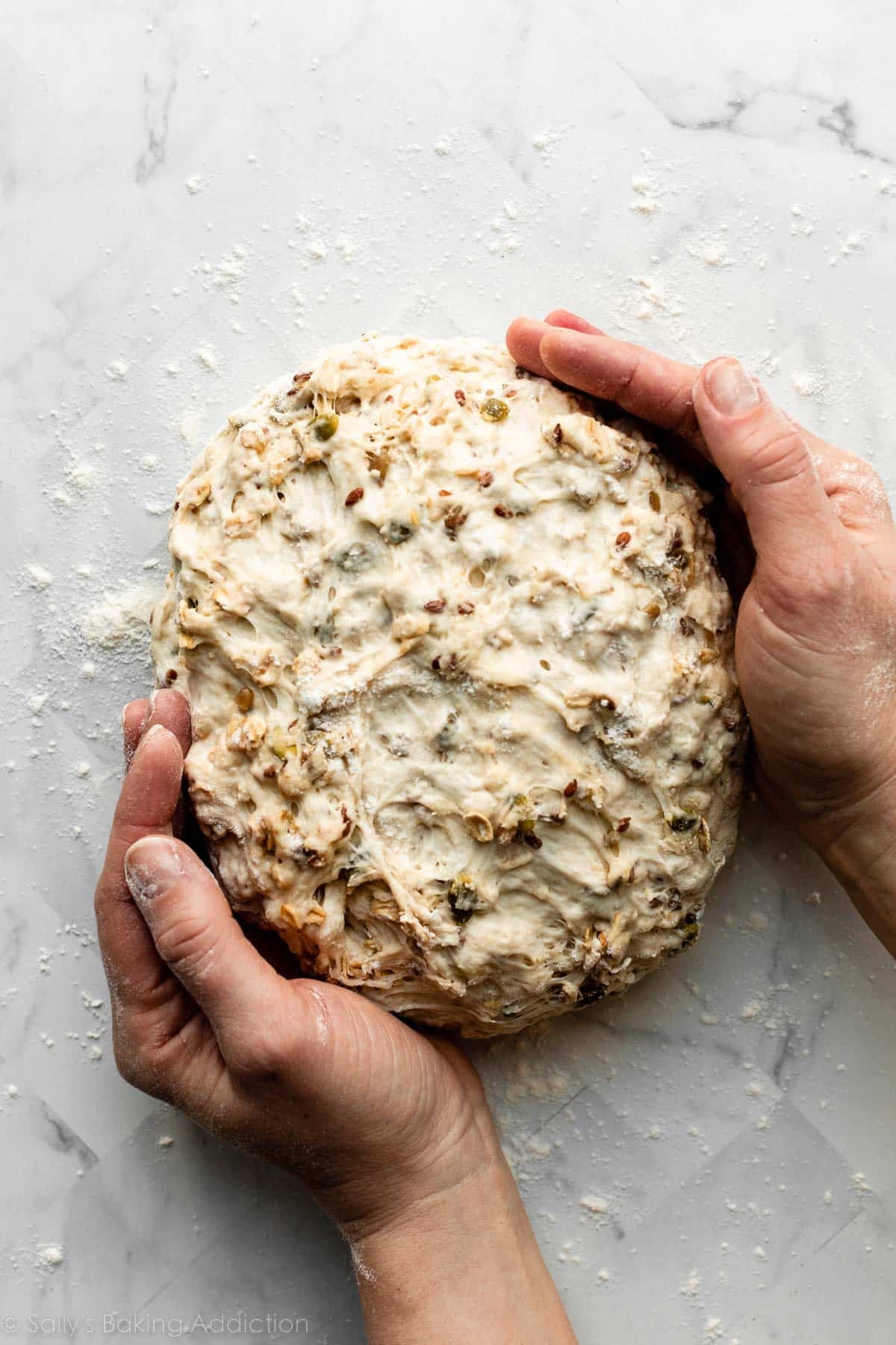 hands shaping round ball of dough on counter.
