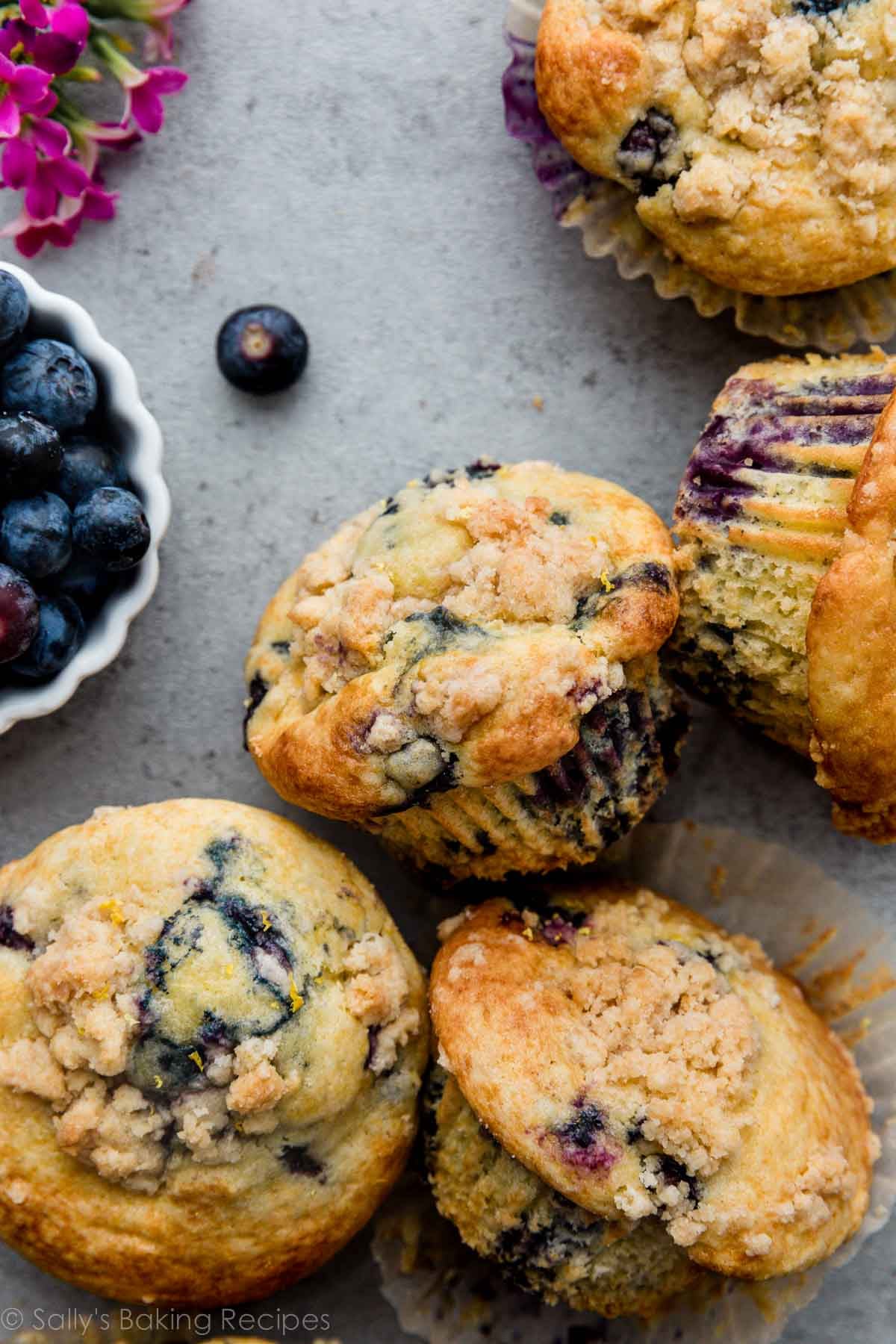 lemon blueberry muffins with crumb topping on gray backdrop.